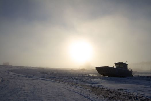 Landing craft centre console aluminum power boat sitting on snow covered beach, near Churchill, Manitoba, Canada