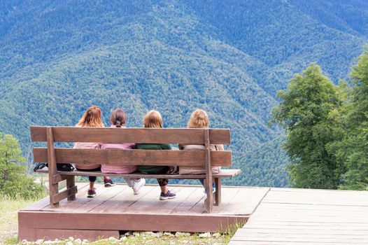 the girls on the bench admire the mountain scenery. photo