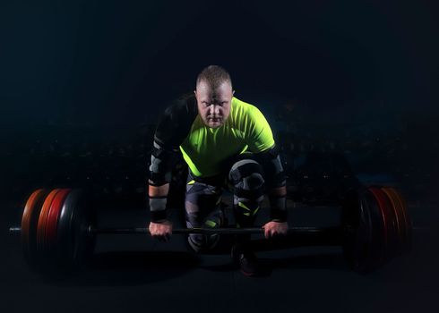 guy athlete bodybuilding goes in for sports in the gym lifts the barbell from the floor concentrated and confident with both hands heavy weight and strong guy fitness creative photo. High quality photo