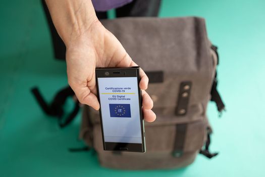 Woman with backpack showing on smartphone Italian EU Digital Covid Certificate.