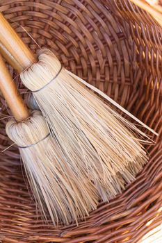 Small eco-friendly handmade brooms In a wicker basket close up background