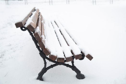 Wooden bench covered with snow. A bench in the park after a snowfall. Winter time, weather phenomenon.