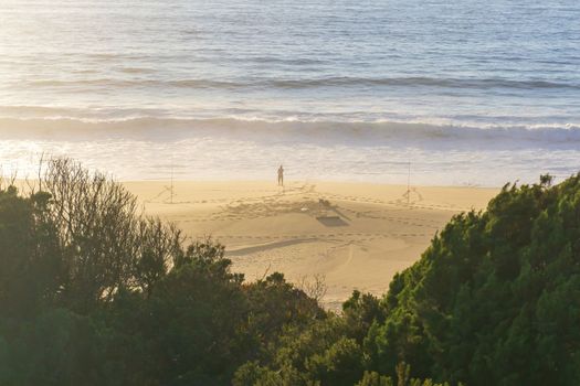 Ocean beach with a lone figure of a fisherman on the shore