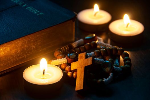 Holy Rosary, Bible and burning candles on dark background. ideas. Religion concept.