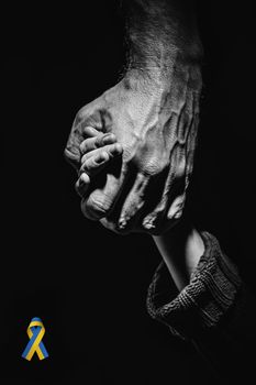male hands hold children hand in dark. black and white color. concept needs help and support, truth will win