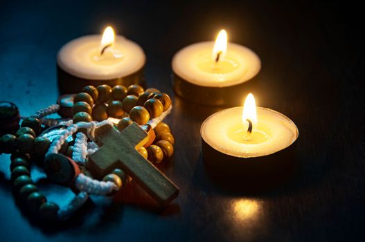 Holy Rosary and burning candles on dark background. ideas. Religion concept.