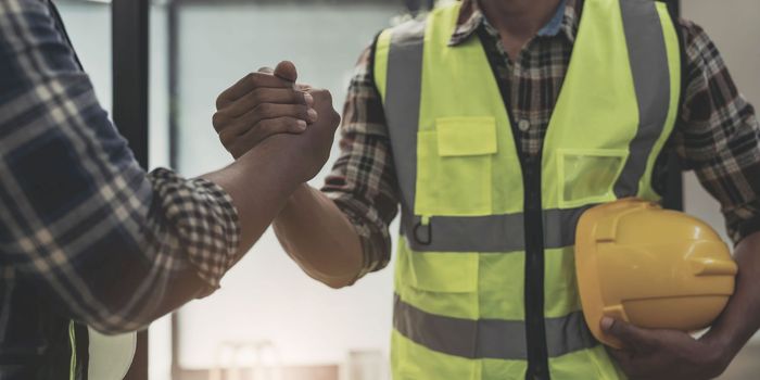 construction worker team hands shaking after consultation meeting to greeting start up plan new project contract in office center at construction site, teamwork, partnership and contractor concept..