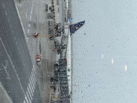 Storm at the airport before onboarding. View of the airplane through rain drops. Themes weather and delay or canceled flight.