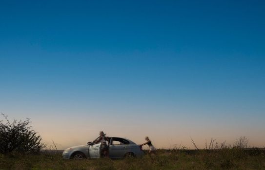 an accident on the road, a car broke down, two beautiful girl models are pushing the car for repairs. High quality photo