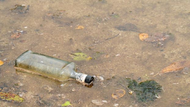 Glass bottle in water, pollution of water bodies, garbage in the sea and river. High quality photo