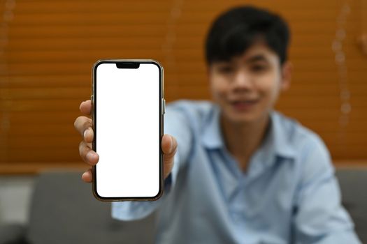 Man hand showing mock up smart phone with white empty screen for your advertise design.
