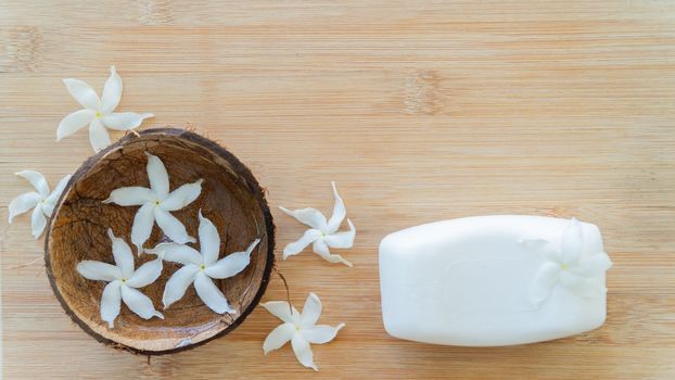 White soap and white flowers in a coconut bowl, spa treatments, background. High quality photo