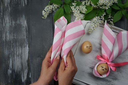 Women's hands decorate Easter eggs in a napkin. Easter bunny. Easter decorations