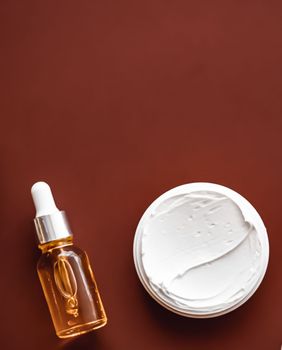 Beauty cosmetics and skincare product on chocolate background, flatlay.