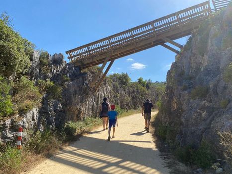 Family on tourist trip in mountains. Boy with his parents hiking in a path in a natural park during summer vacation