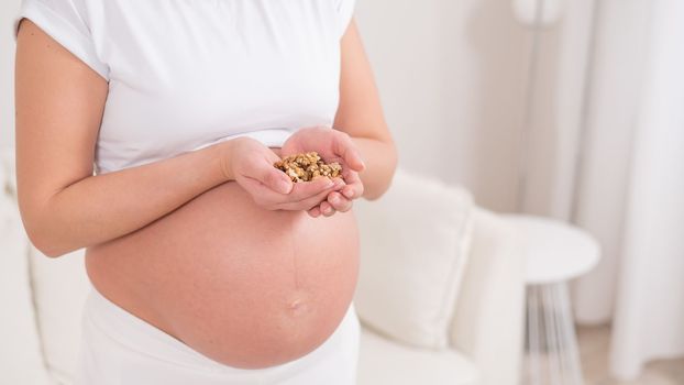 Pregnant woman holding a handful of walnuts