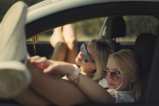 skinny girls eat in the car away from the bustle of the city, best friends are free and enjoy the journey. High quality photo