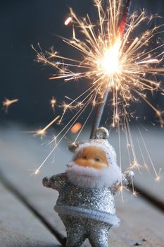 Santa Claus and sparkler on vintage table. Christmas card.