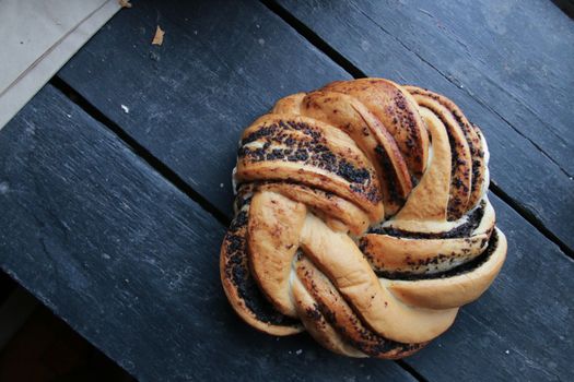 Sweet roll with poppy seeds on a vintage table.