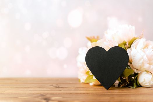 Still life Valentines day festive background with empty black chalkboard heart on wooden background. Mockup with copy space for design.