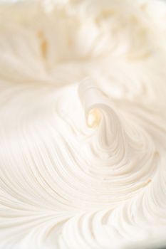 Mixing in store-bought buttercream frosting in a glass mixing bowl.