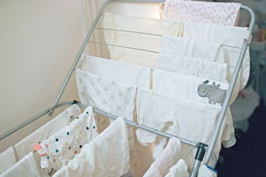 Baby's clothes, bodysuits and pants are dried after the laundry. Organization and cleaning in the children's room.
