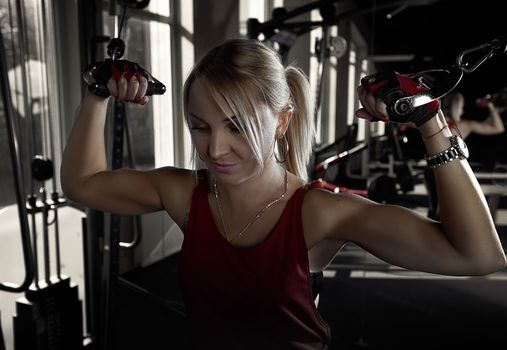 Fitness woman working out in gym doing exercise for biceps. Athletic girl training .Beautiful fitness woman lifting dumbbells . Fitness sporty woman showing her well trained body