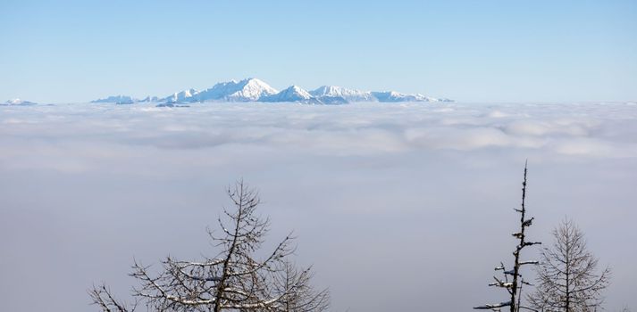 Winter mountains covered with snow landscape over clouds. High quality photo