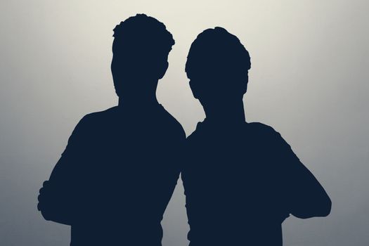 Two male silhouettes in studio. Two men standing together staying anonym hiding their identity. High quality photo