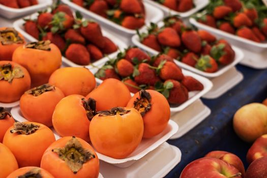 Fresh ripe persimmons placed on table in market. Organic persimmon fruit in pile at local farmers market.