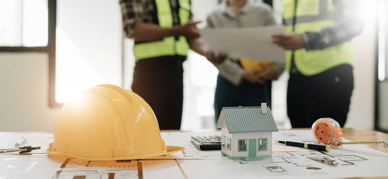 Civil engineer teams meeting working together wear worker helmets hardhat on construction site in modern city. Foreman industry project manager engineer teamwork. Asian industry professional team...