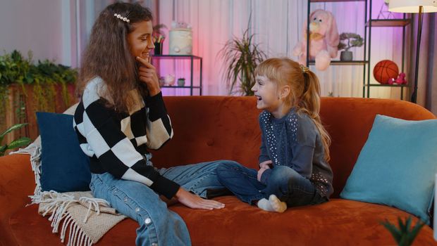 Teenage child and little sister kid talking, making friendly conversation, gossiping, telling storys. Siblings children girls or best friends at home play room. Friendship family relationship concept