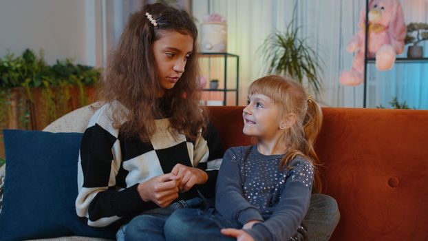 Teenage child and little sister kid chatting talking, make support conversation consulting together. Siblings children girls friends secrets gossip, news rumors having great fun time at home play room