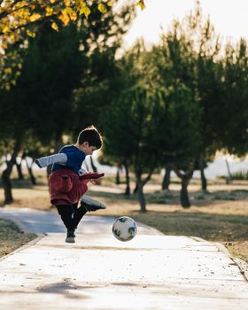 Happy kid jumping enjoying with soccer ball in nature. Freedom and happiness concept.