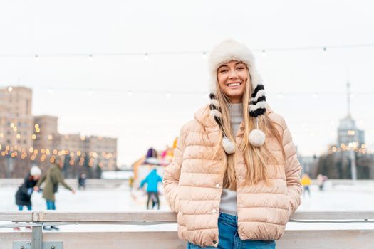 Medium shoot portrait of romantic european lady wears long stylish winter jacket and funny fluffy hat in snowy day. Outdoor photo of inspired blonde woman enjoying free time in winter city. Christmas