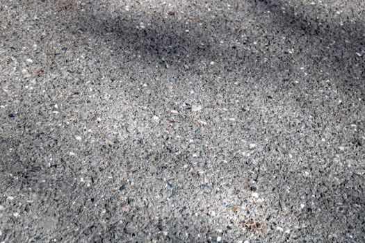 A light wall of stone chips with a shadow falling on it. The texture of the stone. Universal natural background.