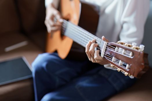 Portrait of young asian woman playing guitar on sofa relaxing stress on vacation.