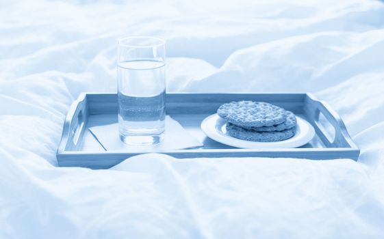 Tray with water and crackers breakfast on a bed