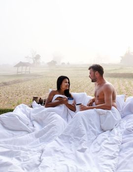 A couple of caucasian men and Asian women at a cottage homestay in an outdoor bed in Northern Thailand Nan Province