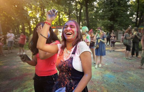 Young people, teenagers and adults celebrate the Holi event in Ukraine in Chernivtsi on March 8 in 2022. They have fun and throw paint at each other. High quality photo