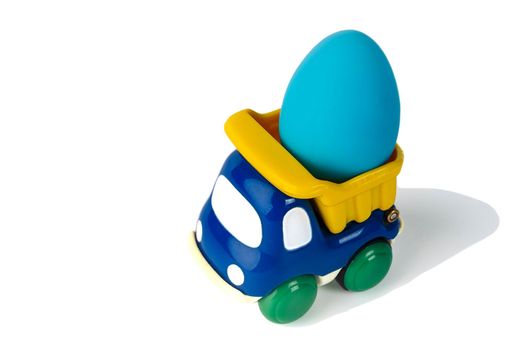 A toy children's dump truck transports an Easter gift egg. isolated on a white background. Kids toy dump truck. Plastic children's toy. close-up