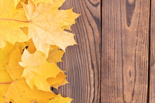 Autumn leaves frame on one left side wooden background top view Fall Border yellow and Orange Leaves vintage wood table Copy space. Mock up for your design. Display for product or text