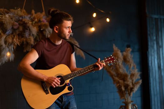 Male musician playing acoustic guitar. Guitarist plays classical guitar on stage in concert Handsome young hipster male guitar player perform private party Stylish long hair Medium shoot