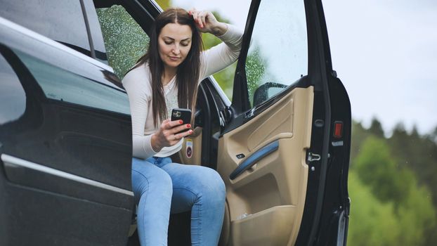A girl is looking through her phone while sitting in her car