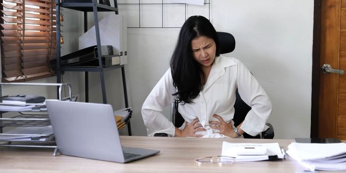 Tired female employee holding head on hand, looking at computer screen, doing hard task, having problem with computer software. Stressed exhausted businesswoman suffering from headache, feeling bored