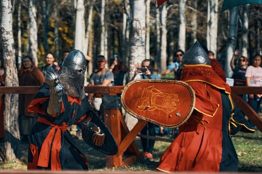 Two knights fight with swords in front of an audience. Festival of jousting tournaments. Simulation of medieval battles during the festival of historical clubs. Bishkek, Kyrgyzstan-October 13, 2019.