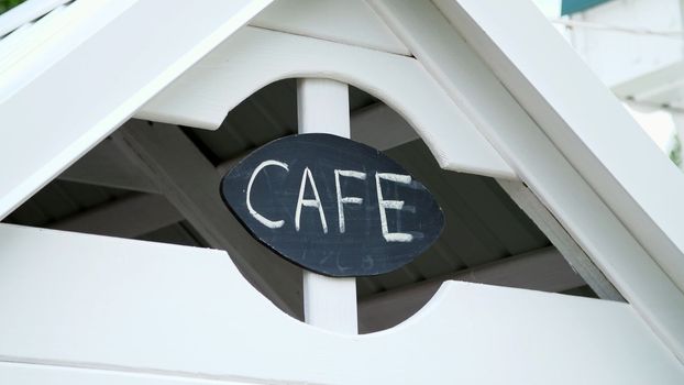 a sign on a children's play house, an inscription of a cafe, on a black board written in white chalk word-cafe. High quality photo