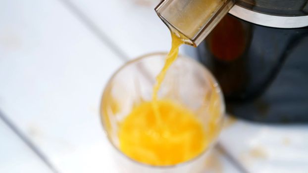 close-up, from the juicer flows freshly squeezed orange juice into a glass. view from above. High quality photo