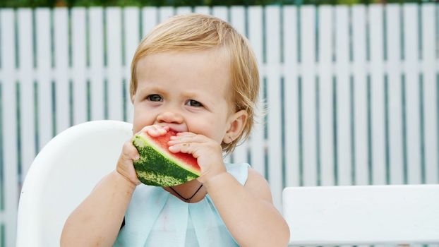 summer, in the garden, funny one-year-old blond girl eating watermelon. High quality photo