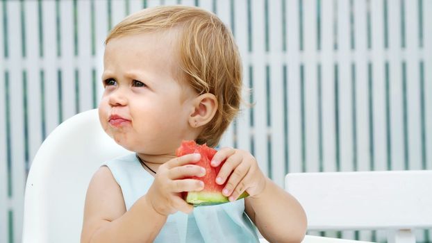 summer, in the garden, funny one-year-old blond girl eating watermelon. High quality photo
